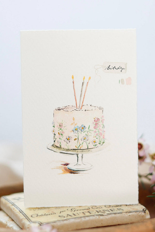 Greeting card with a cake illustration and floral details on a white background