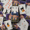 A flat-lay arrangement of Halloween-themed playing cards and a matching card deck box on a dark background. The cards feature whimsical illustrations of haunted houses, witches, skeletons, pumpkins, bats, and spiders in bright colors.