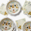 A coordinated baby shower tableware set featuring scalloped paper plates and napkins with a whimsical safari-themed embroidery design. The set includes a teddy bear, giraffes, trees, balloons, and a small house, with 'Sweethearts One' embroidered on the napkins.