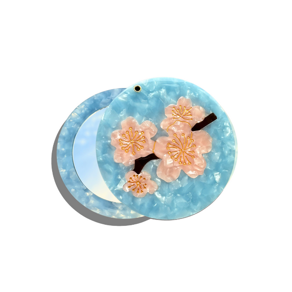 Decorative hair clip with cherry blossom design on a light blue background