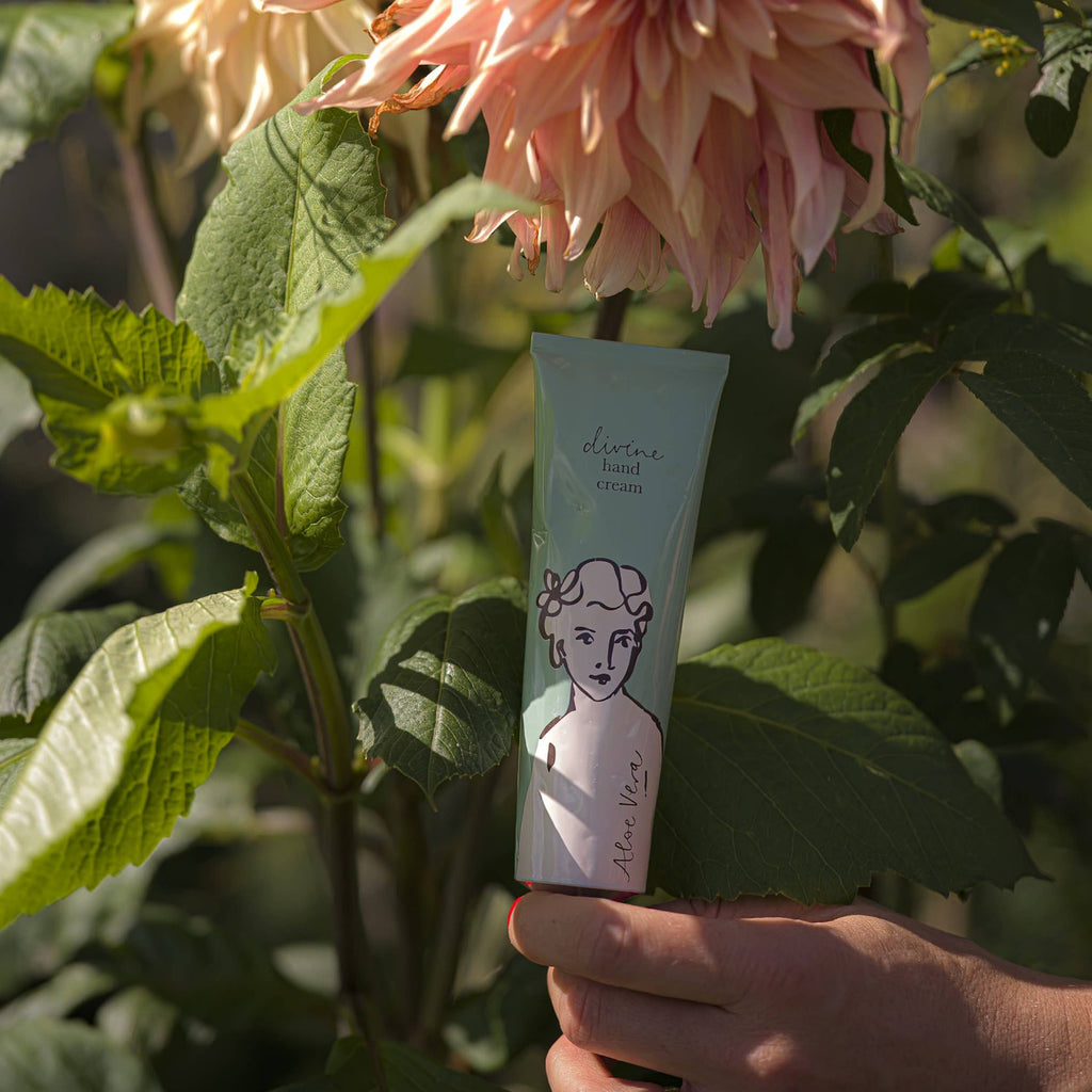 Hand holding a tube of cream with floral background