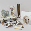 Collection of stationery items including cards, envelopes, and a pen on a light gray background