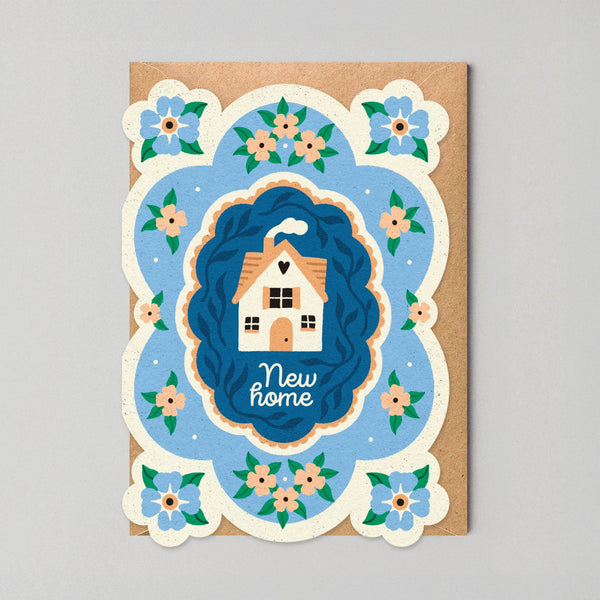 Greeting card with a house illustration and 'New home' text on a blue background, surrounded by floral elements.