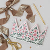 Floral-patterned paper crown with gold scissors and ribbons on a light background