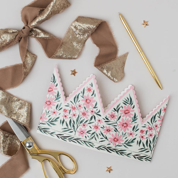 Floral-patterned paper crown with gold scissors and ribbons on a light background
