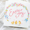Easter-themed card with chicks, flowers, and 'Easter Joy' text on a white fabric background.