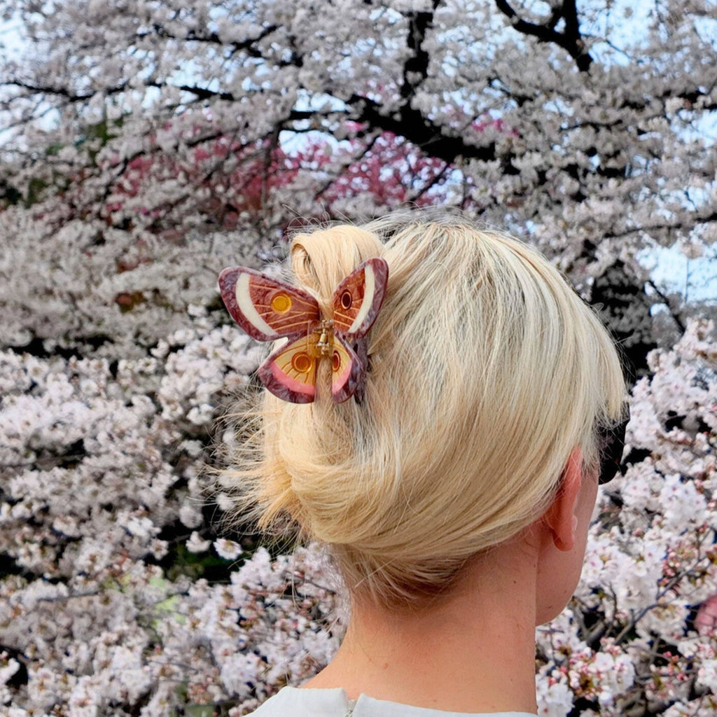 Person with a butterfly hair accessory in front of cherry blossom trees