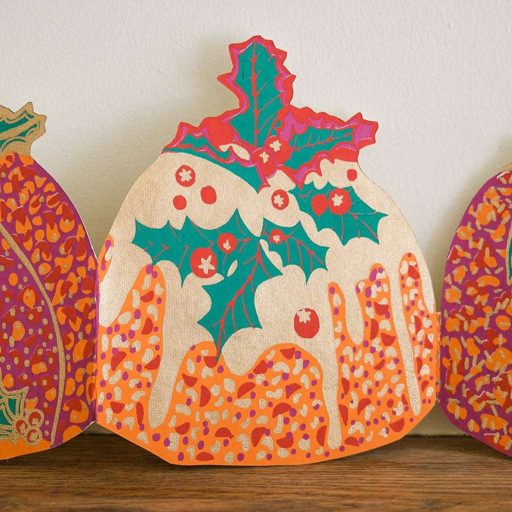 Decorative paper pumpkins with festive patterns on a wooden surface.