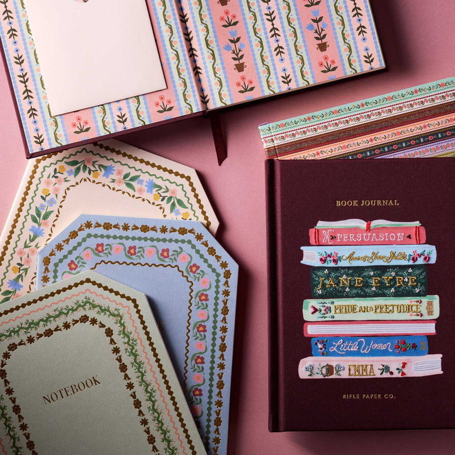 Collection of notebooks and journals with decorative covers on a pink background