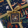 Gift wrapped in festive paper with a gold ribbon and Christmas-themed label.