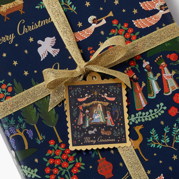 Gift wrapped in festive paper with a gold ribbon and Christmas-themed label.