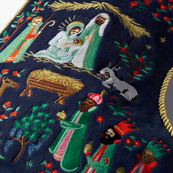 Embroidered nativity scene with Mary, Joseph, and baby Jesus on a dark blue background.