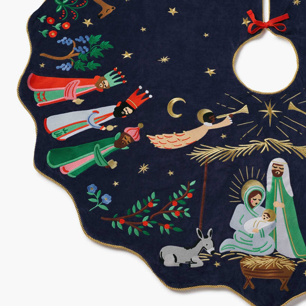 Decorative Christmas tree skirt with nativity scene design on a dark blue background.