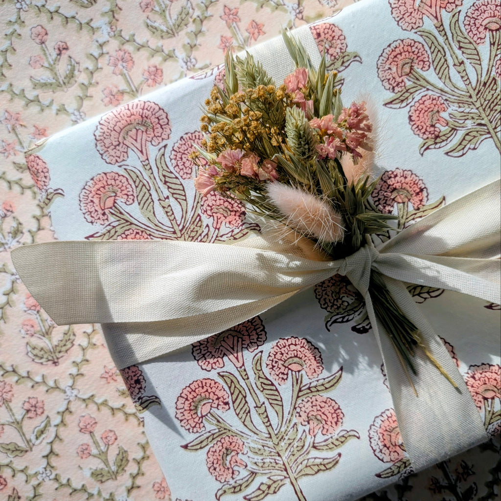 Gift wrapped in floral-patterned paper with a decorative bow on a floral background