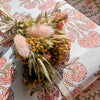 Decorative floral arrangement with pink fluffy elements on a patterned fabric background