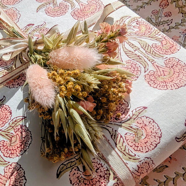 Decorative floral arrangement with pink fluffy elements on a patterned fabric background