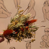 Dried floral arrangement held in front of a patterned background with human figures.