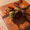 Gift wrapped in brown paper with floral patterns and a decorative bow.