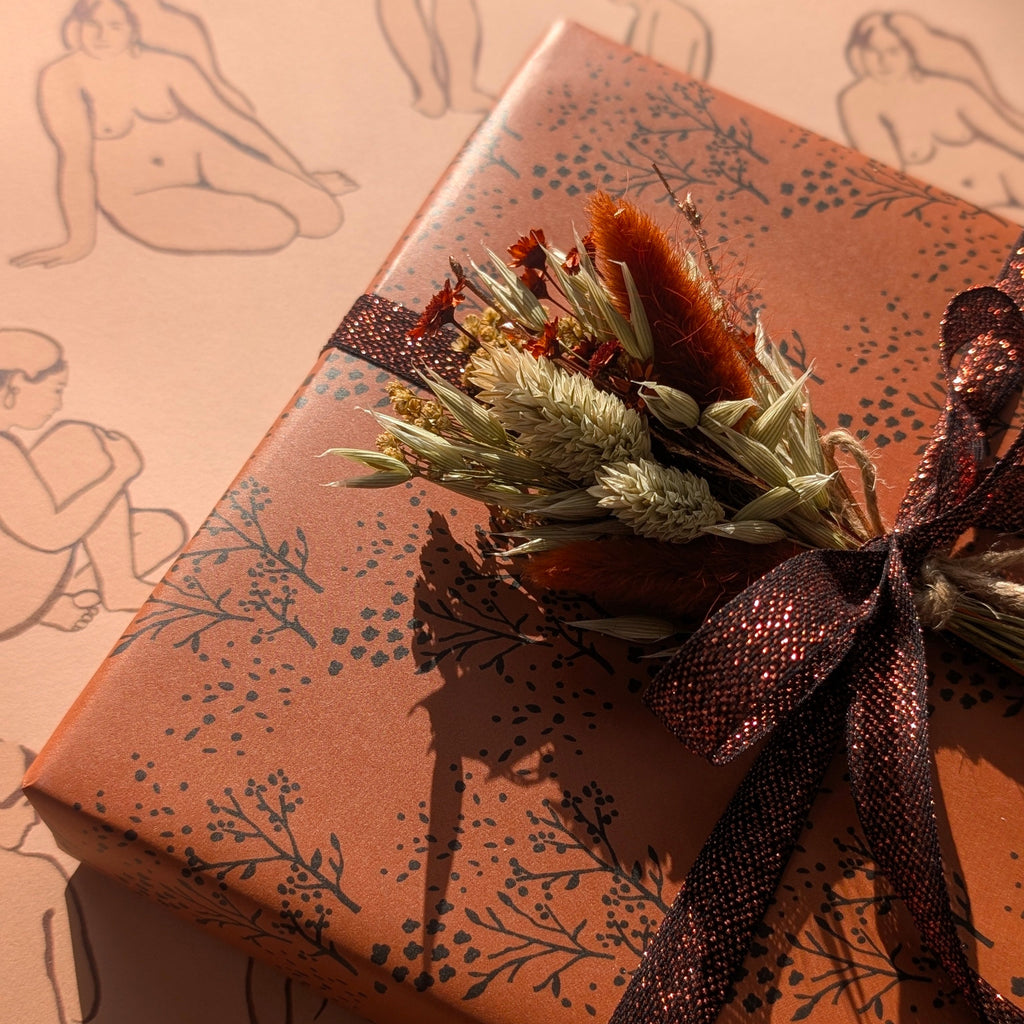 Gift box with floral arrangement and decorative ribbon on patterned background